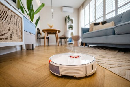 Téléchargez les photos : Robotique aspirateur nettoyage plancher en bois dans le salon - en image libre de droit