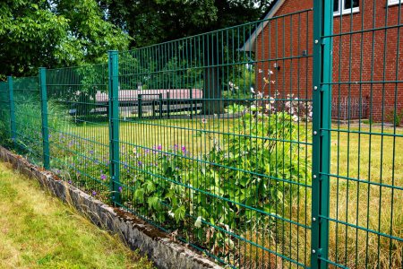 Photo for Garden behind fence with flowers growing in the center of the fence in Germany. - Royalty Free Image