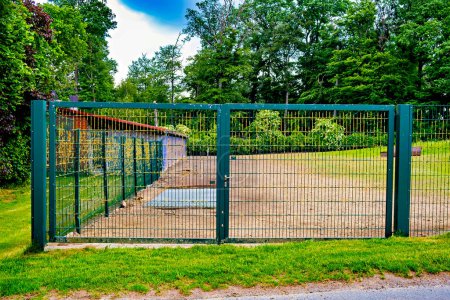 Photo for Fenced area green mesh metal fence with a gate. - Royalty Free Image