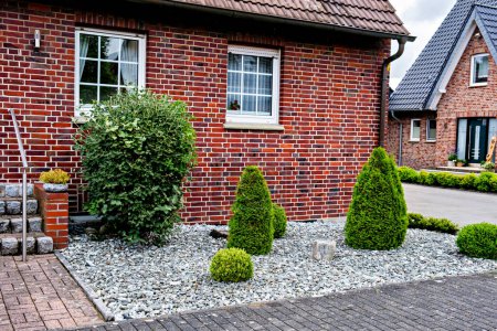 Téléchargez les photos : Beau paysage décoratif d'arbustes et de pierres près d'une maison de briques résidentielles en Allemagne. - en image libre de droit