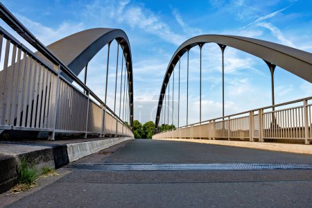 Bridge with two arches spans gap under blue sky.