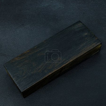 Foto de Madera aserrada de rara madera de ébano con un hermoso patrón para artesanías sobre fondo negro - Imagen libre de derechos