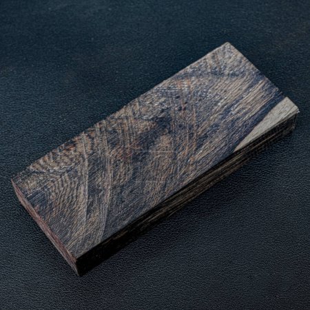 Foto de Madera aserrada de rara madera de ébano con un hermoso patrón para artesanías sobre fondo negro - Imagen libre de derechos