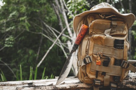Foto de Una mochila de cuchillo con equipo para la supervivencia en el bosque en una madera vieja - Imagen libre de derechos