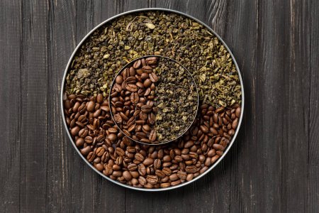 Photo for Green dry tea and roasted coffee beans in two round plates of different sizes one on top of the other on a dark wooden background top view close-up. Conceptual composition of green tea and coffee beans on a dark background with space for text. - Royalty Free Image