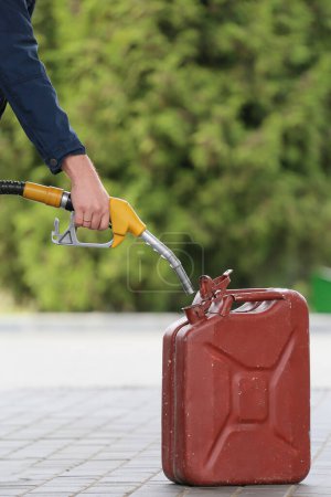 Photo for A man fills jerry cans at a gas station. A man fills gasoline in a canister at a gas station. Pouring gasoline into a canister. Collecting funds to buy fuel. - Royalty Free Image