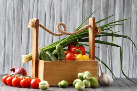 Foto de Tomatoes, cucumbers, peppers, Brussels sprouts, onions and garlic in a wooden basket. Basket with vegetables on a wooden background. The concept of organic products, proper, healthy nutrition. - Imagen libre de derechos