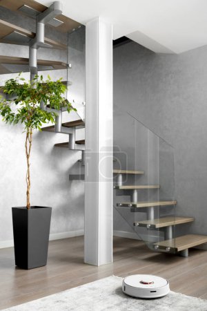 Foto de Una escalera con escalones de madera y una elegante valla de vidrio, una columna de vidrio mate, gran flor interior en el interior moderno del apartamento. Diseño de escaleras en un apartamento de dos niveles. - Imagen libre de derechos