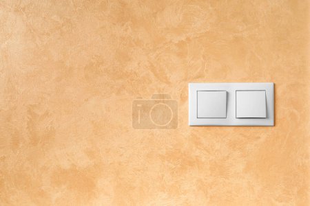 Foto de Doble interruptor de plástico blanco para electricidad en el fondo de un primer plano de pared de textura con espacio para texto. - Imagen libre de derechos