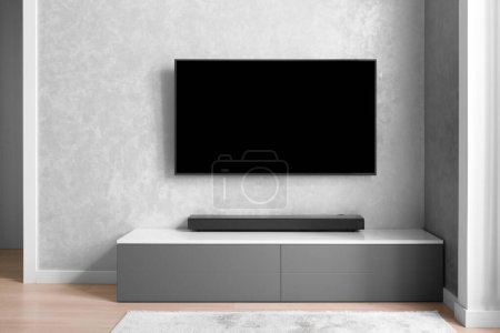 Photo for Part of the interior of the living room with a TV on the wall, hifi equipment, Sound bar, gray cabinet. TV and music system in the interior. Modern living room in bright colors. Minimalism in the interior. - Royalty Free Image
