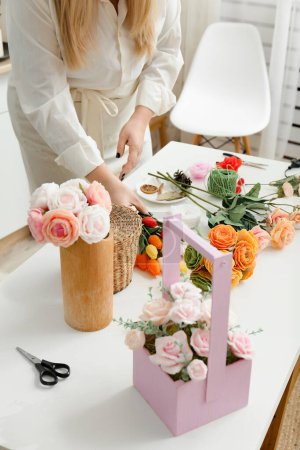 Téléchargez les photos : Girl makes flowers from the soap. Hobby, creative process. DIY gifts. Women's hands and flowers. Handmade soap. Mother's Day, Women's Day. Natural organic products. Flowers on a white table. - en image libre de droit