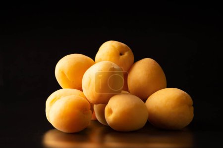 Foto de A handful of ripe apricots on a dark background. Useful fruit. Pineapple apricots on black background - Imagen libre de derechos