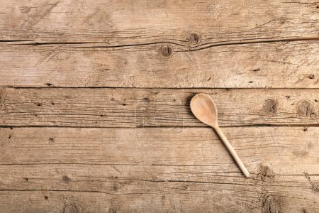 Photo for Wooden kitchen spoon on an aged wooden background top view with space for text. - Royalty Free Image