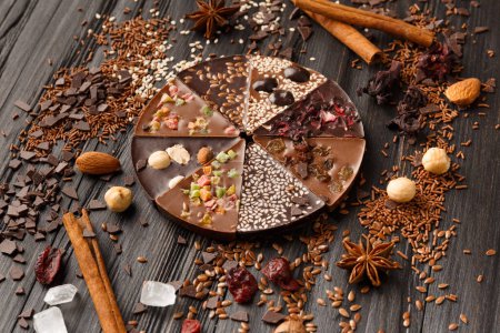 Photo for Creative composition chocolate in the shape of a pizza with candied fruits, nuts, dry berries, chocolate pizza and ingredients on a dark wooden background. - Royalty Free Image