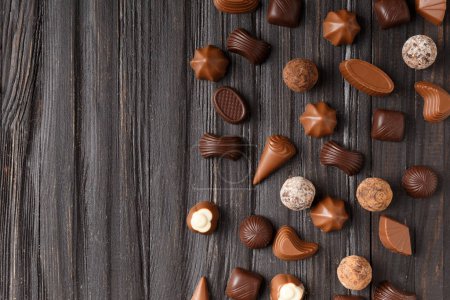 Photo for Various dark and milk chocolate candies, chocolate truffles on a dark wooden texture background top view with space for text. - Royalty Free Image