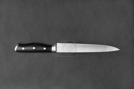 Foto de Kitchen knife with a black handle on a black background. Large knife on a dark background. Kitchenware. Knife with a wide blade. - Imagen libre de derechos