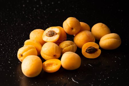 Photo for A handful of ripe apricots with drops of water on a dark background. Useful fruit. Pineapple apricots on black background - Royalty Free Image