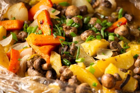 Téléchargez les photos : Oiseau cuit avec des champignons et des pommes de terre sur un fond sombre. Canard grillé appétissant aux légumes sur fond noir - en image libre de droit