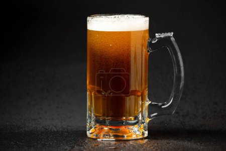 Foto de Cerveza ligera sin filtrar en un vaso sobre una vieja mesa de madera sobre un fondo oscuro con lugar para texto - Imagen libre de derechos