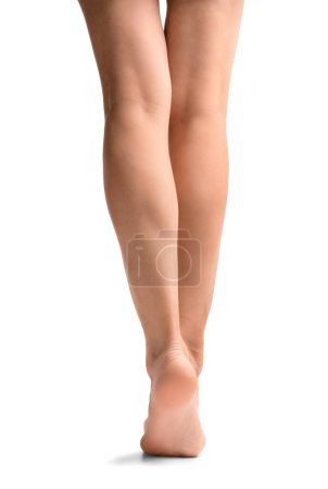 Téléchargez les photos : Slender female legs on a white background rear view. Woman's feet isolated. Foot skin care, depilation, pedicure, hygiene. - en image libre de droit