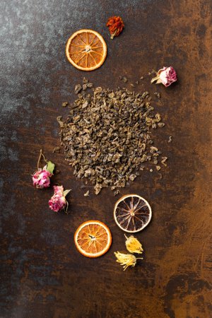 Photo for Green dry tea, flower tea and dry orange chips on brown background top view. Different types of tea and dry citrus slices on a dark background. - Royalty Free Image