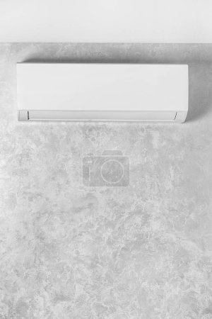 Téléchargez les photos : Climatiseur blanc sur un mur gris dans une maison, appartement. Système de climatisation. L'unité intérieure d'un système de séparation pour le refroidissement et le chauffage de la pièce. Climatiseur mural. - en image libre de droit