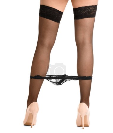 Photo for Legs of a girl in black stockings and high-heeled shoes takes off black lace panties close-up on a white background - Royalty Free Image