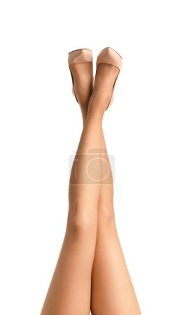 Foto de Patas femeninas delgadas en medias beige transparentes y elegantes zapatos de tacón alto beige se levantan sobre un fondo blanco, aislados. Un primer plano de las elegantes piernas de la chica, bellamente apuntando hacia arriba - Imagen libre de derechos