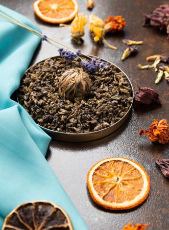 Photo for Composition of green, flower tea and dried orange slices on blue and brown backgrounds. Large-leaf tea, dried flowers and citrus chips on contrasting backgrounds. - Royalty Free Image