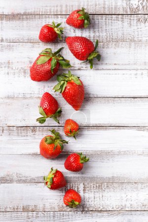 Photo for Berries of large ripe fresh organic strawberries on a wooden background close-up, top view, with space for text. - Royalty Free Image