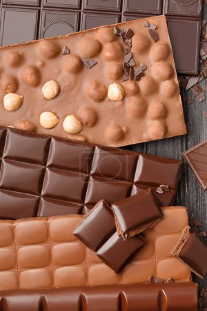 Foto de Surtido de barras de chocolate y dulces sobre un fondo de madera oscura. Concepto de confitería, variedad de chocolate. - Imagen libre de derechos