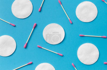 Photo for Cotton pads and pink cotton swabs are laid out on a blue background, top view. Hygiene, makeup, medicine. - Royalty Free Image