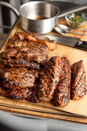 Photo for Various types of delicious, juicy grilled steaks on a wooden board in a restaurant. Ribeye steak, tenderloin cooked on fire. B-B-Q. - Royalty Free Image