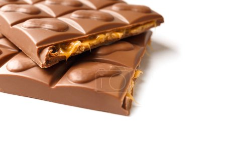 Photo for A chocolate bar broken in half with caramel and nut filling on a white background, close-up, copy space. - Royalty Free Image