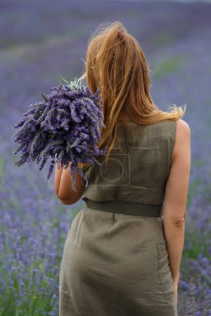 Téléchargez les photos : Une fille avec un grand bouquet de fleurs de lavande dans un champ de lavande. - en image libre de droit
