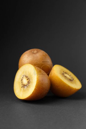 Photo for Whole and halved ripe golden kiwi isolated on black background. Kiwi with yellow juicy sweet pulp (Actinidia chinensis). - Royalty Free Image