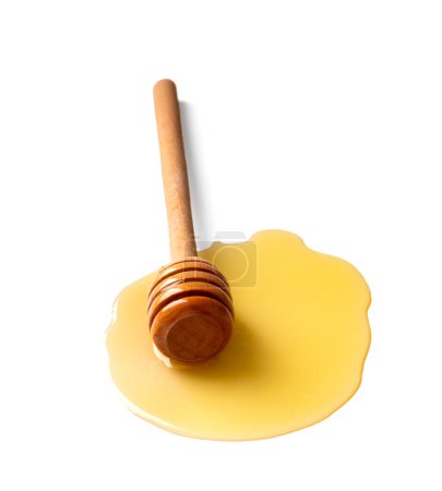 Téléchargez les photos : Une trempette en bois se trouve dans du miel renversé sur un fond blanc gros plan. Cuillère à miel dans une goutte de miel sur l'isolement. - en image libre de droit