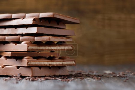 Photo for Chocolate bars on a dark wooden background. Broken chocolate lies in a stack. - Royalty Free Image