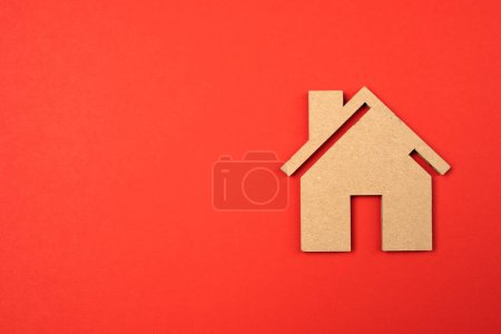 Téléchargez les photos : Simple petit jouet maison fait maison pour le carton. Isolé sur fond rouge. Espace de copie, macro. - en image libre de droit