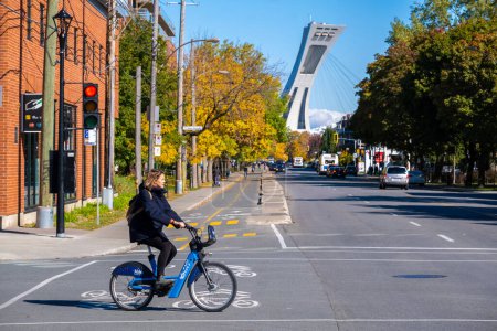 Foto de Montreal, CA - 10 de octubre de 2022: Mujer montando una bicicleta Bixi en la calle Rachel en otoño - Imagen libre de derechos