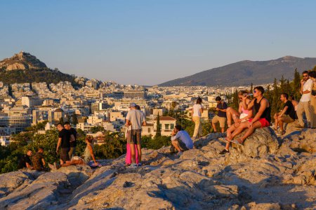 Foto de Atenas, GR - 29 de julio de 2023: La gente mirando la puesta de sol en la colina del Areópago - Imagen libre de derechos