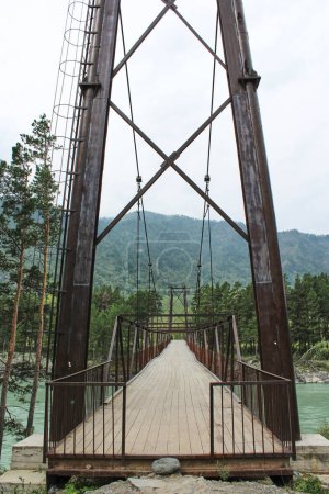 Eiserne Hängebrücke für Fußgänger über den Fluss. Vertikales Foto