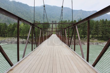 Holzdeck auf einer eisernen Hängebrücke für Fußgänger über den Fluss.