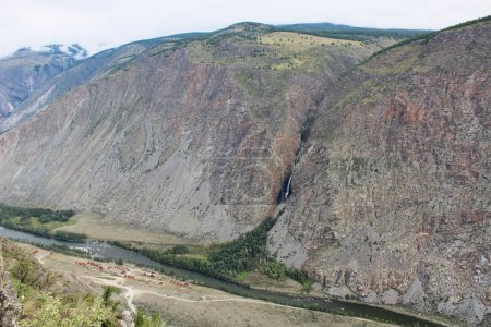 Vue du col Katu-Yaryk à la vallée de Chulyshman. Hautes montagnes avec une cascade, une rivière et un centre de loisirs en contrebas. Saison estivale dans les montagnes Altaï