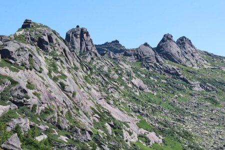 Bergrücken aus felsigen Gipfeln, überwachsen mit grünen Sträuchern und Moos in bergigem Gebiet. Ergaki-Nationalpark, Region Krasnojarsk, Sajan-Gebirge, Russland. 