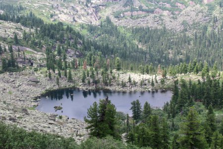 Blick von oben auf den Kleinen Teich zwischen grünen Wäldern und Felsen. Hudozhnikov-See im Sajan-Gebirge, Naturpark Ergaki, Region Krasnojarsk, Sibirien, Russland. Top-Panoramablick, Sommerlandschaft