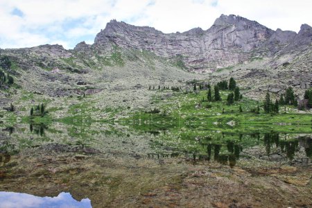 Die Ausdehnung des Wassers des Bergsees Mramornoje mit der symmetrischen Reflexion der hohen felsigen Gipfel. Ergaki Naturpark. Sommerliche Naturlandschaft. Ein Ort zum Wandern, Klettern und Meditieren