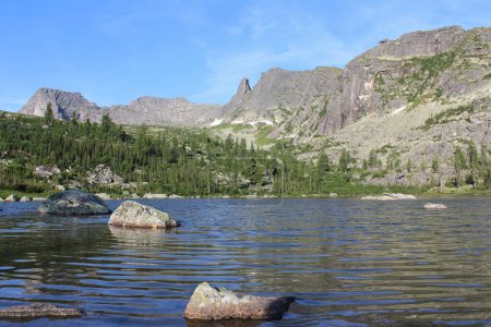 Bergsee Raduzhnoye, Blick auf hohe felsige Klippen, hängende Steine und schlafende Sajan im Ergaki Naturpark. Sibirien, Russland. Sommerliche Naturlandschaft. Wilder Tourismus