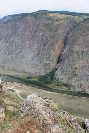 Blick vom Katu-Yaryk Pass auf das Chulyshman Tal. Hohe Berge mit einem Wasserfall, einem Fluss und einem Erholungszentrum. Sommersaison im Altai. Vertikales Foto