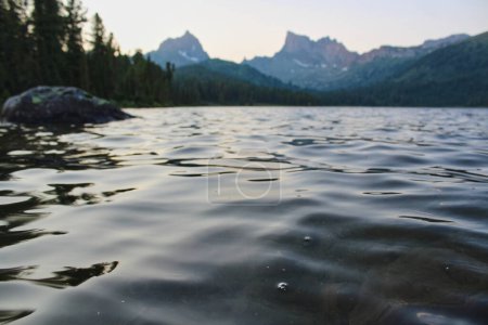 Rippling water in mountain lake Svetloye. Twilight on Shore of pond in Ergaki nature park. Summer mountains landscape, Siberia, Russia. 